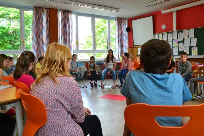 Schülerinnen und Schüler sitzen im Klassenraum in einem großen Stuhlkreis