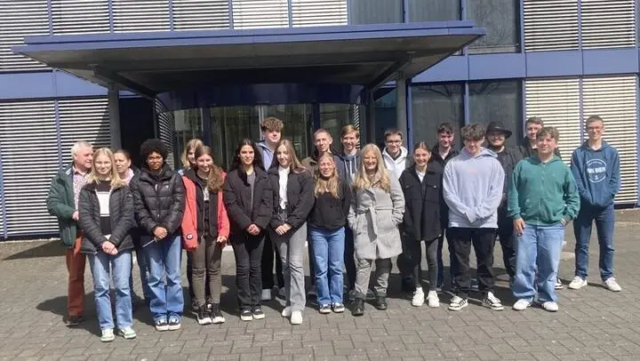 Gruppenfoto von Schülerinnen und Schülern mit Begleitpersonen vor dem Eingang eines Gebäudes