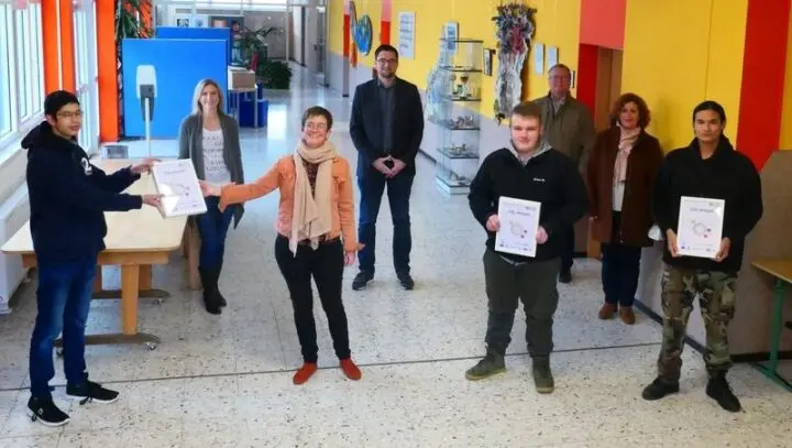Schüler übergeben im Schulflur gerahmte CO2-Ampeln an Erwachsene