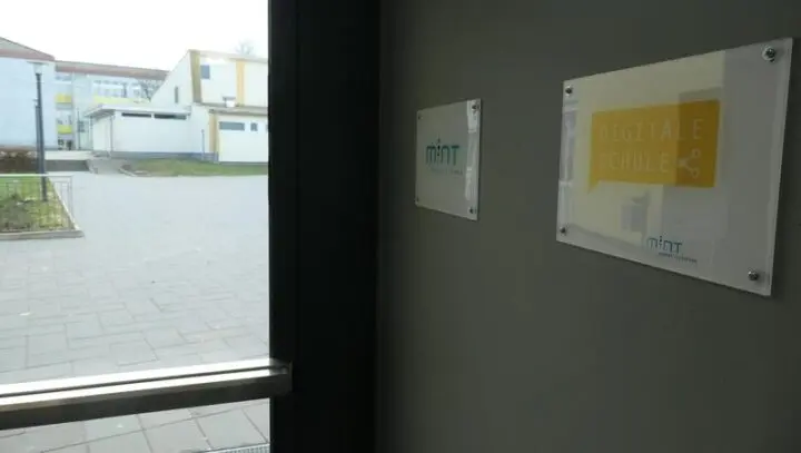 Blick aus der Eingangstür auf den Schulhof, an der Wand Schilder „MINT“ und „Digitale Schule“