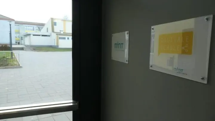 Schilder „MINT“ und „Digitale Schule“ an der Wand neben einer Eingangstür