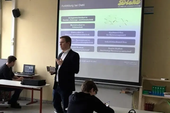 Ein Mann präsentiert vor Schülern die Folie „Ausbildung bei Diehl“ mit Ausbildungsberufen