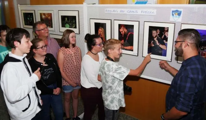 Gruppe betrachtet ausgestellte Fotos an einer Stellwand „Foto-AG der GemS Freisen“