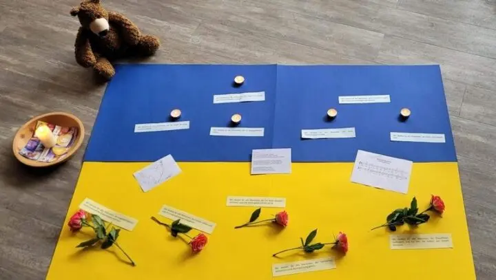 Papier in Blau und Gelb mit Teelichtern, Rosen, Textkarten und Teddybär auf dem Boden