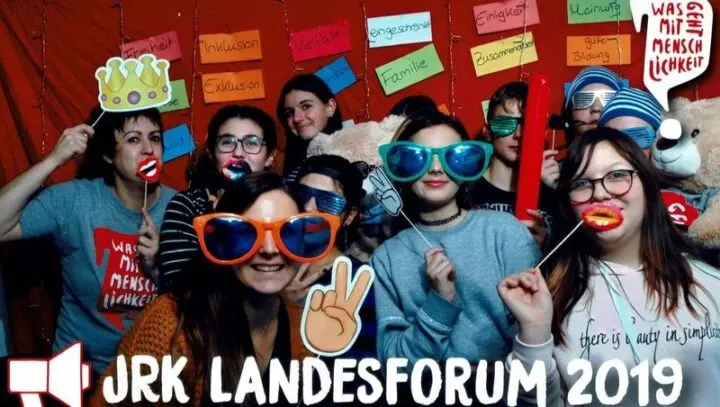 Fotobox-Bild: Jugendliche mit Spaßbrillen und Requisiten vor Wortkarten wie „Vielfalt“, Schriftzug „JRK Landesforum 2019“