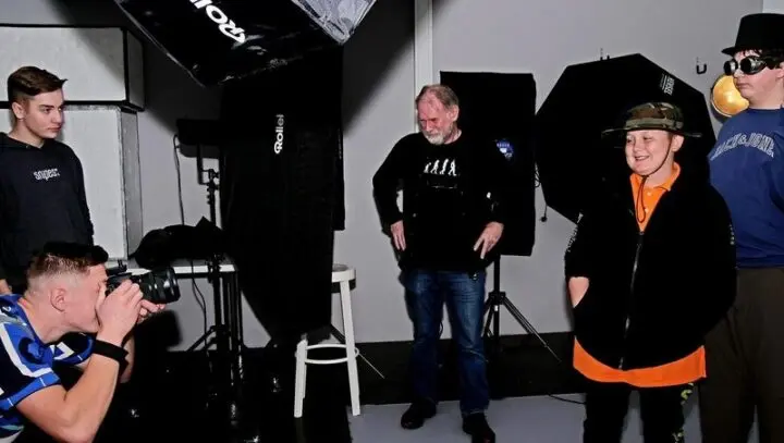 Jugendlicher fotografiert im Studio zwei verkleidete Jugendliche, ein Erwachsener schaut zu