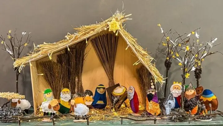 Weihnachtskrippe mit Strohdach und bunten Filzfiguren: Heilige Familie, Hirten, Schafe und Könige