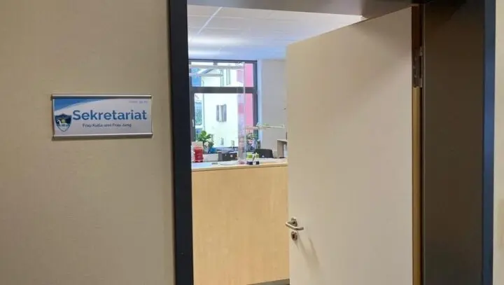 Geöffnete Tür zum Sekretariat mit Theke und Türschild „Sekretariat“