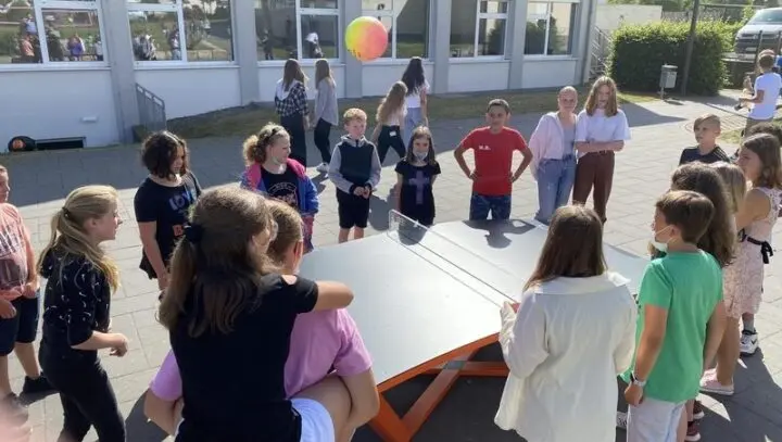 Schülerinnen und Schüler stehen um eine Teqball-Platte auf dem Schulhof, ein Ball fliegt