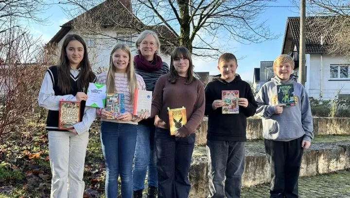 Fünf Schülerinnen und Schüler halten draußen Bücher hoch, darunter Harry Potter, dahinter eine Frau