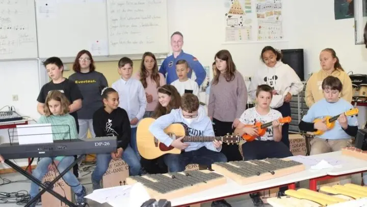 MusiKlasse mit Gitarre, Ukulelen und Xylofonen im Musikraum, dahinter Pappaufsteller eines Astronauten