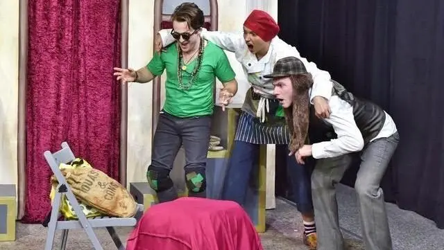 Drei Schauspieler bei einer Theateraufführung auf der Bühne, einer mit Sonnenbrille vorneweg